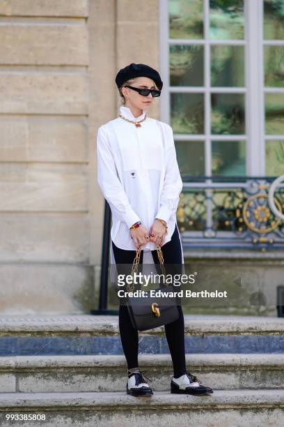 Caroline Daur wears a black beret hat, a white shirt, a Dior bag, outside Dior, during Paris Fashion Week Haute Couture Fall Winter 2018/2019, on...
