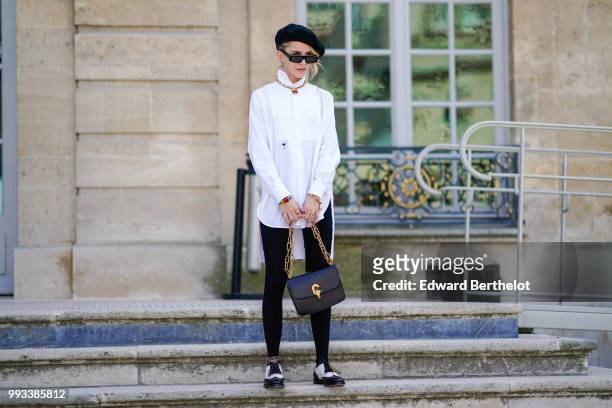 Caroline Daur wears a black beret hat, a white shirt, a Dior bag, outside Dior, during Paris Fashion Week Haute Couture Fall Winter 2018/2019, on...