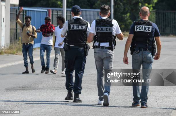 Police officers walk next to migrants in Calais on July 7, 2018. - Several hundred people took part in a "solidarity" march in support of migrants in...