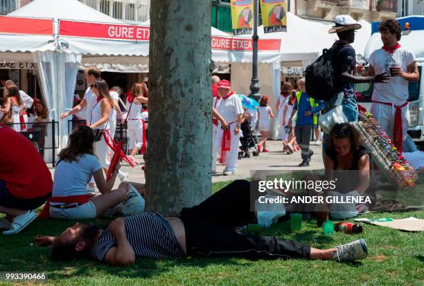 Revellers rest on the first day of the San Fermin bull run festival in Pamplona, northern Spain on July 7, 2018. - Each day at 8am hundreds of people...