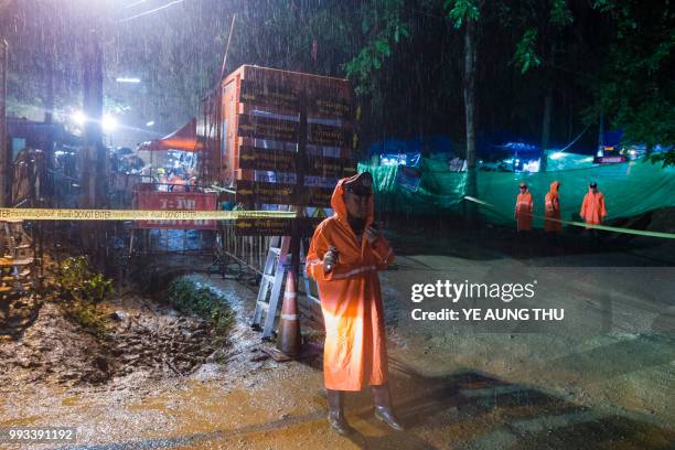 Thai policeman guards an area under rainfall near the Tham Luang cave at the Khun Nam Nang Non Forest Park in Mae Sai district of Chiang Rai province...