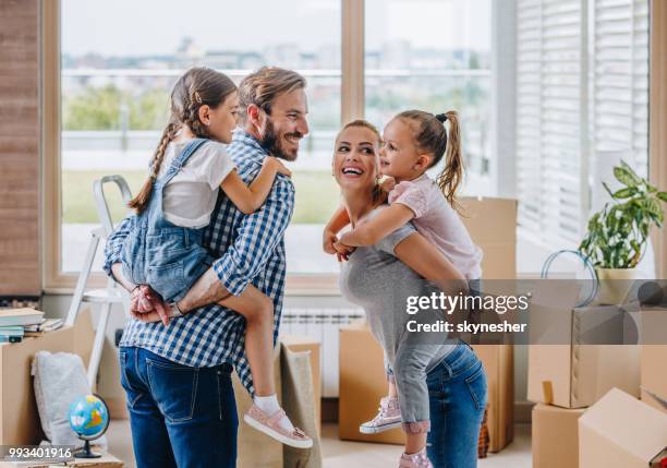 happy family talking and piggybacking while moving into new apartment. - penthouse girl stock pictures, royalty-free photos & images