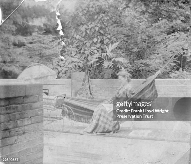 Catherine Wright sitting in a hammock on the front porch of the Home, baby carriage and chair also visible, at the Frank Lloyd Wright Home and...