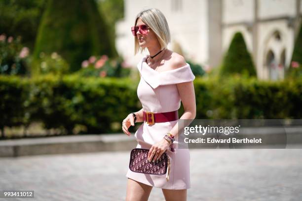 Sofie Valkiers wears sunglasses, a pink dress, a Dior clutch, a red belt, silver shoes , outside Dior, during Paris Fashion Week Haute Couture Fall...