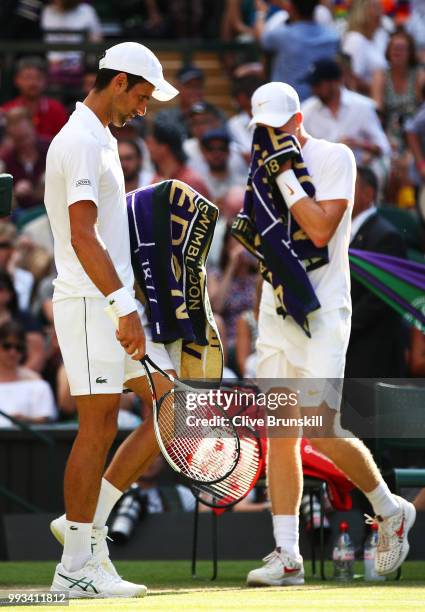 Novak Djokovic of Serbia and Kyle Edmund of Great Britain walk past eachother during a break in play in their Men's Singles third round match on day...