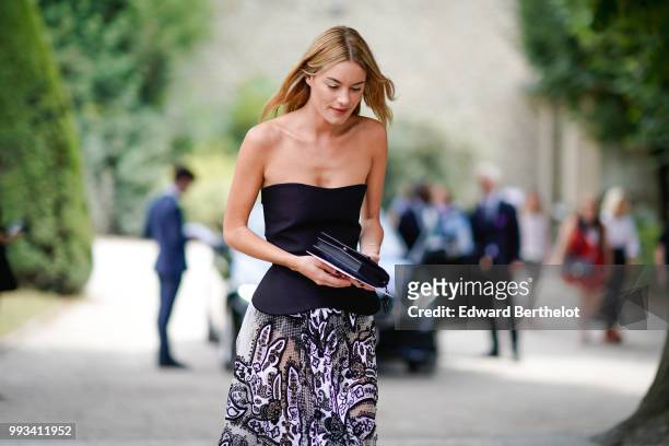 Camille Rowe wears a black off-shoulder top, a pleated lace mesh skirt , outside Dior, during Paris Fashion Week Haute Couture Fall Winter 2018/2019,...