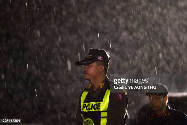 Thai policeman guards an area under rainfall near the Tham Luang cave at the Khun Nam Nang Non Forest Park in Mae Sai district of Chiang Rai province...