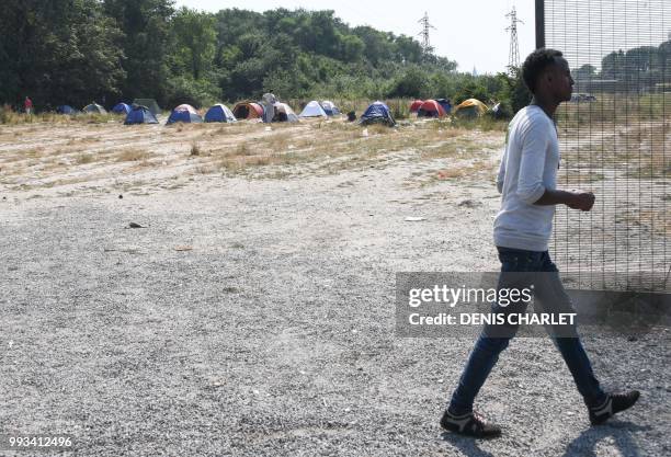 Migrant walks by tents in Calais on July 7, 2018. - Several hundred people took part in a "solidarity" march in support of migrants in Calais,...