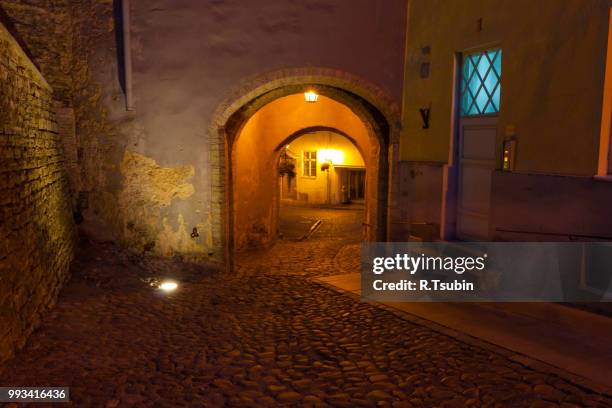 illuminated street in old part of tallinn by night - cobblestone puddle stock pictures, royalty-free photos & images