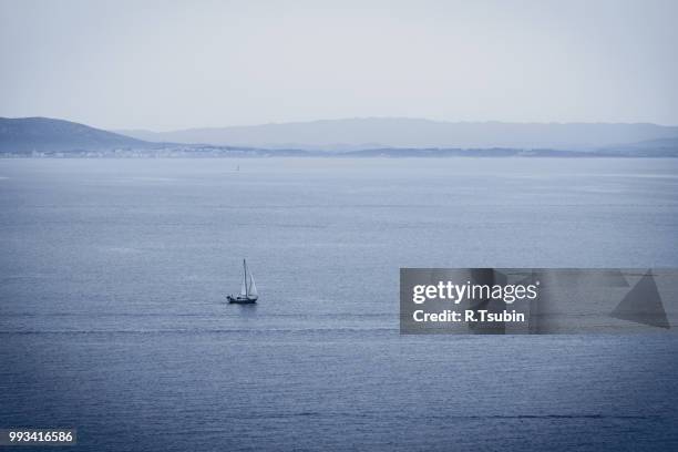 lonely sailboat in sea and mountains at background - jib stock pictures, royalty-free photos & images