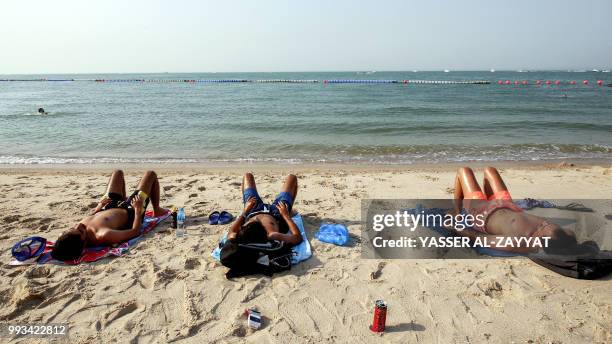 Sunbathers lie on the beach in Salmiya district, some 20 kilometres east of the capital Kuwait City on July 7, 2018. - Temperatures regularly soar in...