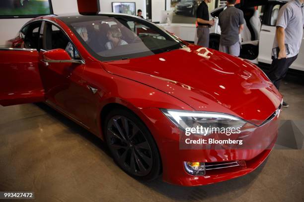 Customers view a Tesla Inc. Model S electric vehicle on display at the company's showroom in Newport Beach, California, U.S., on Friday, July 6,...