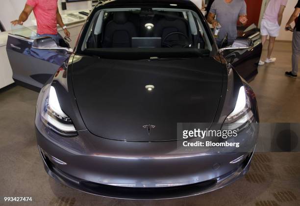 Customers view a Tesla Inc. Model 3 electric vehicle on display at the company's showroom in Newport Beach, California, U.S., on Friday, July 6,...