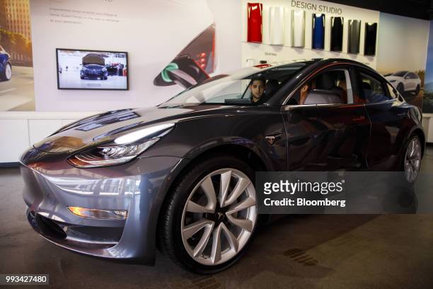 Customers view a Tesla Inc. Model 3 electric vehicle on display at the company's showroom in Newport Beach, California, U.S., on Friday, July 6,...