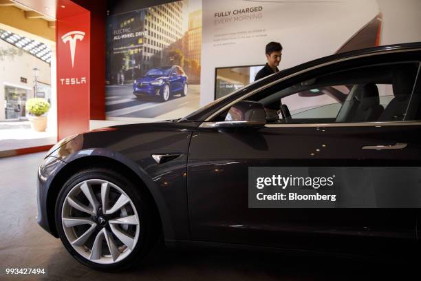 An employee cleans a Tesla Inc. Model 3 electric vehicle on display at the company's showroom in Newport Beach, California, U.S., on Friday, July 6,...