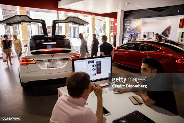 An employee speaks with a customer at the Tesla Inc. Showroom in Newport Beach, California, U.S., on Friday, July 6, 2018. Tesla Inc. Reached a...