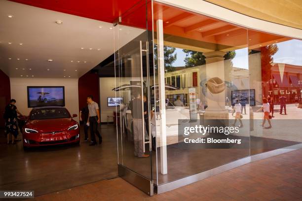 Customers view a Tesla Inc. Model S electric vehicle on display at the company's showroom in Newport Beach, California, U.S., on Friday, July 6,...