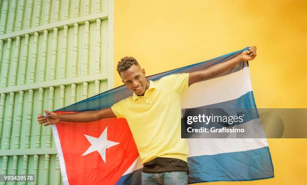 cuban man smiling looking at camera in cuba old havana with cuban flag - grafissimo stock pictures, royalty-free photos & images