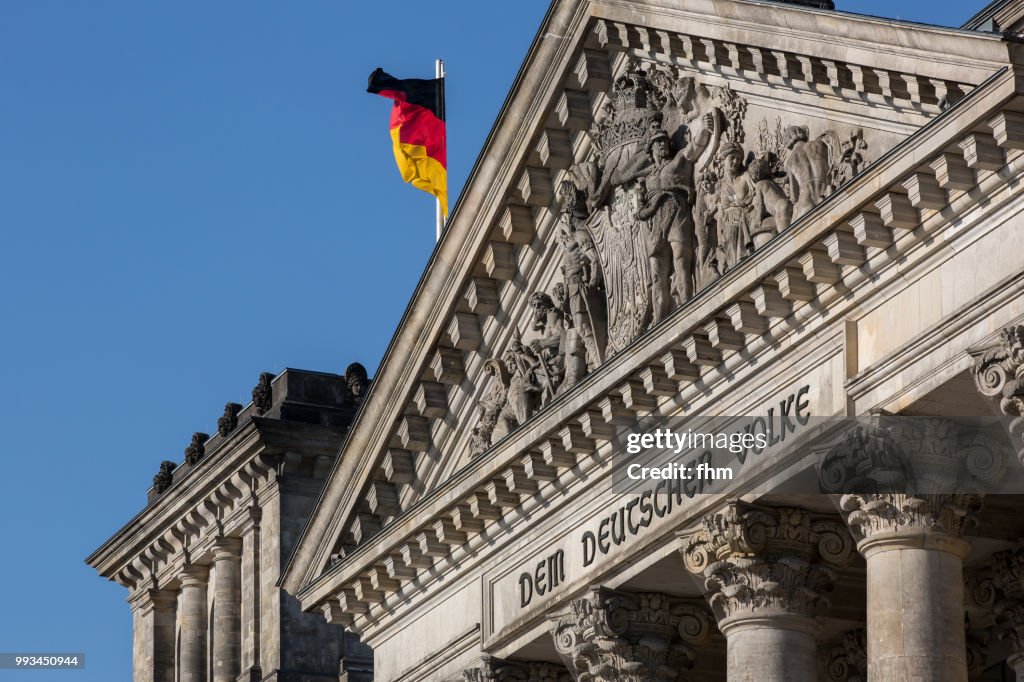 The famous inscription on the architrave on the west portal of the Reichstag building in Berlin: "Dem Deutschen Volke" with german flag
