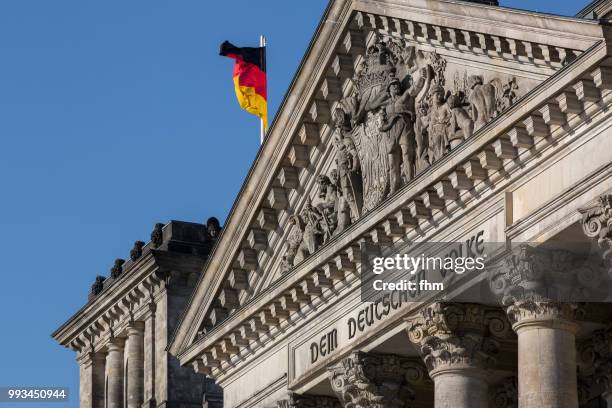 the famous inscription on the architrave on the west portal of the reichstag building in berlin: "dem deutschen volke" with german flag - architrave stock pictures, royalty-free photos & images