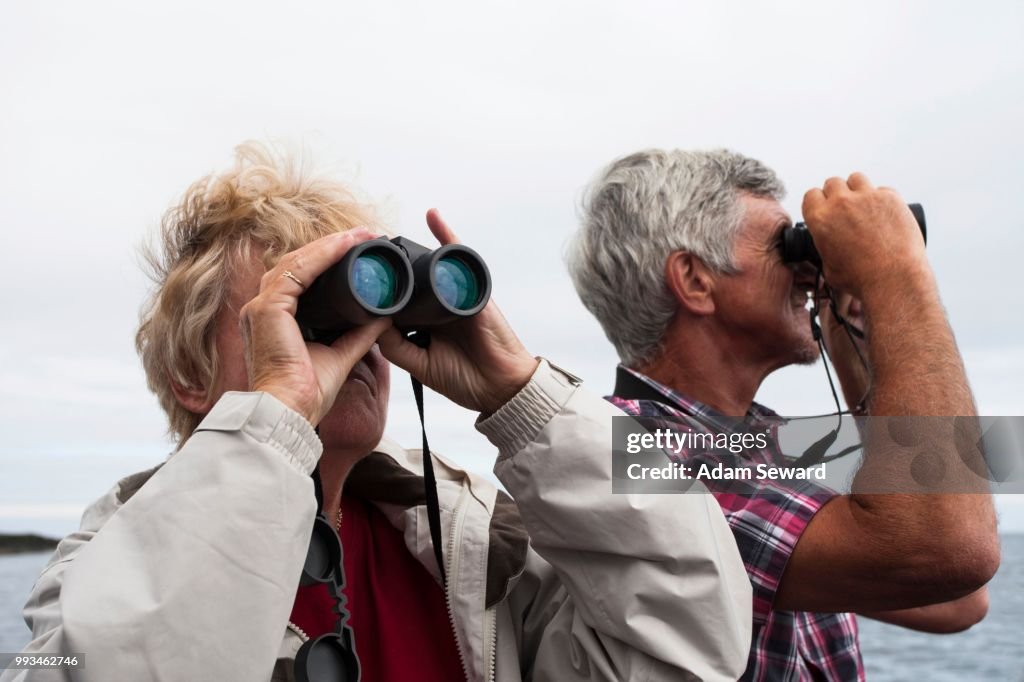 Couple, 60-65 years, using binoculars, Northumberland, England, United Kingdom