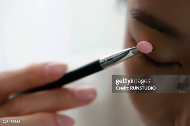 close-up of woman applying eyeshadow - runstudio foto e immagini stock