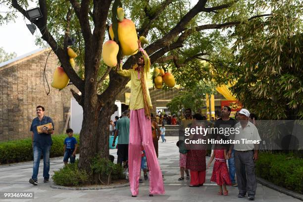 Man touches the artificial mangoes placed on a tree during Mango Festival at Dilli Haat in Janakpuri, on July 7, 2018 in New Delhi, India. The three...