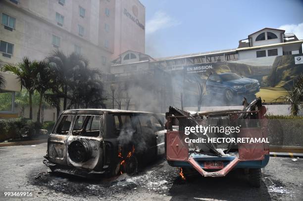 Cars burn in a hotel parking lot in Port-au-Prince after protesters set them on fire on July 7 during a demonstration against the government's...