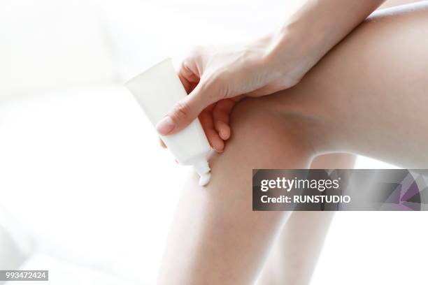 woman applying moisturizer on leg - runstudio foto e immagini stock