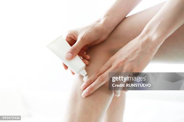 woman applying body lotion on leg - creme corporal imagens e fotografias de stock