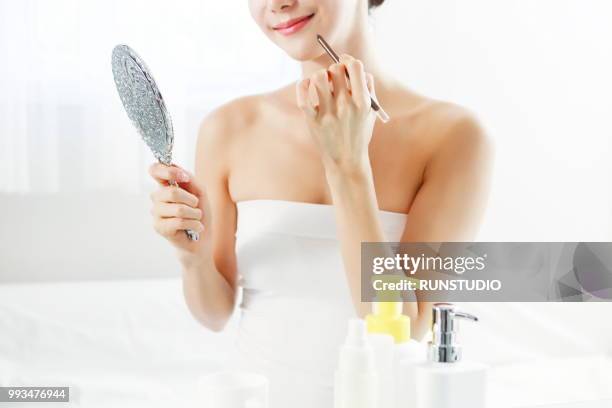 woman applying concealer with mirror - runstudio foto e immagini stock