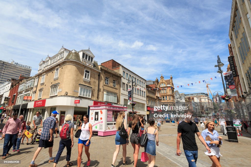 Los amantes de las compras caminando en un área de Leeds pedestrianised