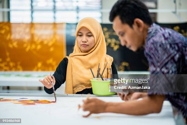 dos personas color batik en su taller - colouring fotografías e imágenes de stock