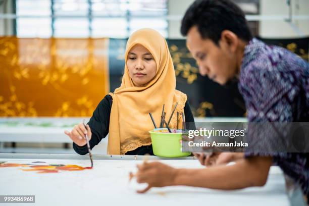 twee mensen kleuren batik in hun werkplaats - colouring stockfoto's en -beelden