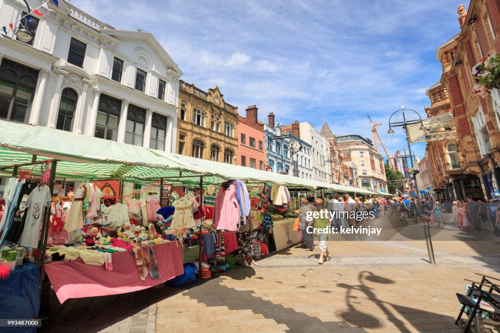 Outdoor market and shoppers walking in a pedestrianised area of Leeds