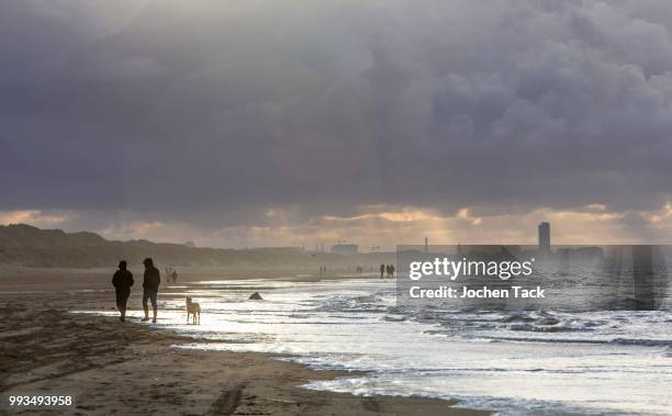 walkers, north sea beach, stormy sea, stormy clouds during an autumn storm, de haan, flanders, belgium - haan stock pictures, royalty-free photos & images