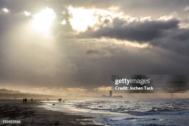 walkers, north sea beach, stormy sea, stormy clouds during an autumn storm, de haan, flanders, belgium - haan stock pictures, royalty-free photos & images