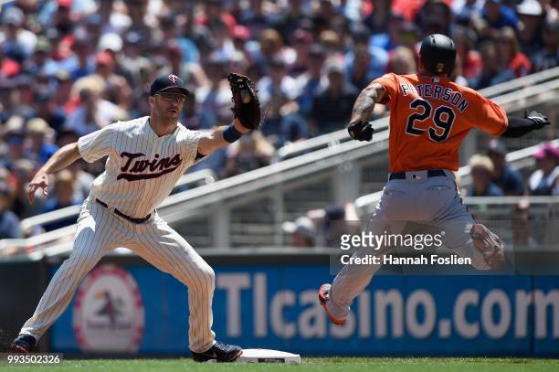 Jace Peterson of the Baltimore Orioles is out at first base as Joe Mauer of the Minnesota Twins fields the ball during the second inning of the game...
