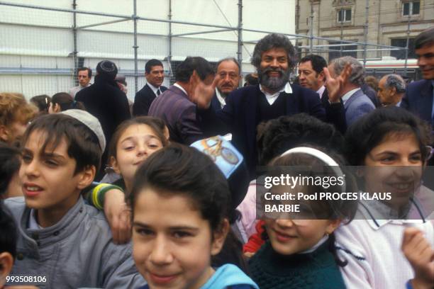 écrivain Marek Halter entouré d'enfants lors de l'ouverture du procès de Klaus Barbie le 11 mai 1987 à Lyon, France.