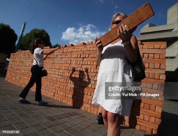 Visitors help to dismantle and take a brick from Mexican artist Bosco Sodi's artwork Muro, a wall built on London's South Bank to protest against US...