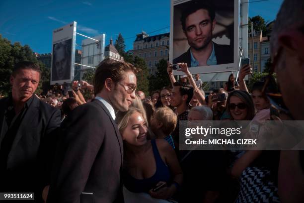 British actor Robert Pattinson poses for photos with his fans as he arrives on the red carpet during the closing ceremony at the 53rd Karlovy Vary...