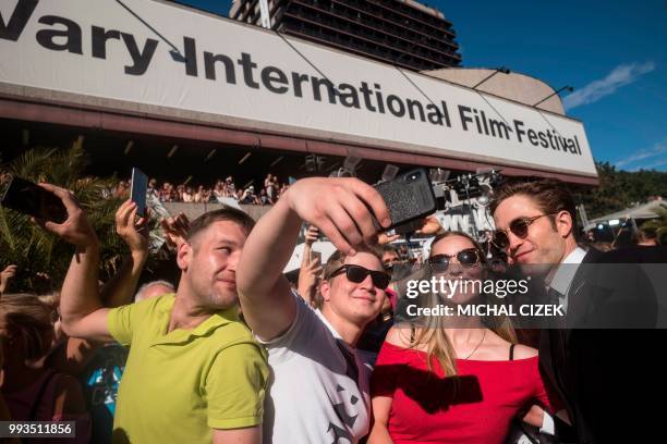 British actor Robert Pattinson poses for photos with his fans as he arrives on the red carpet during the closing ceremony at the 53rd Karlovy Vary...