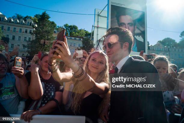 British actor Robert Pattinson poses for photos with his fans as he arrives on the red carpet during the closing ceremony at the 53rd Karlovy Vary...