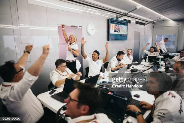 In this handout from Mercedes GP - Lewis Hamilton of Great Britain and Mercedes GP celebrates with team mates in their engineering room in the F1...