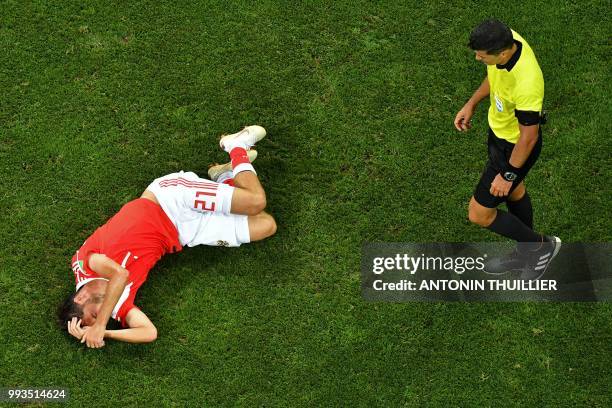 Russia's midfielder Aleksandr Erokhin lies on the pitch next to Brazilian referee Sandro Ricci during the Russia 2018 World Cup quarter-final...