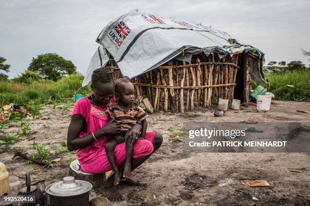 Picture taken on July 3 shows a woman cooking maize and sorghum dropped from air by a World Food Programme plane in Jeich village in Ayod County,...