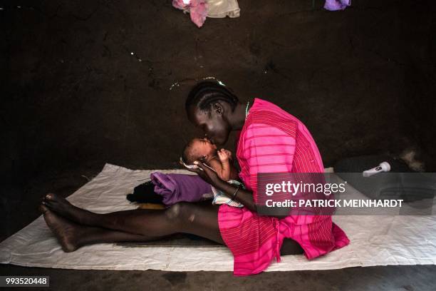 Picture taken on July 3 shows a woman taking care of her new-born baby at her home after a World Food Programme plane dropped sacks of maize and...