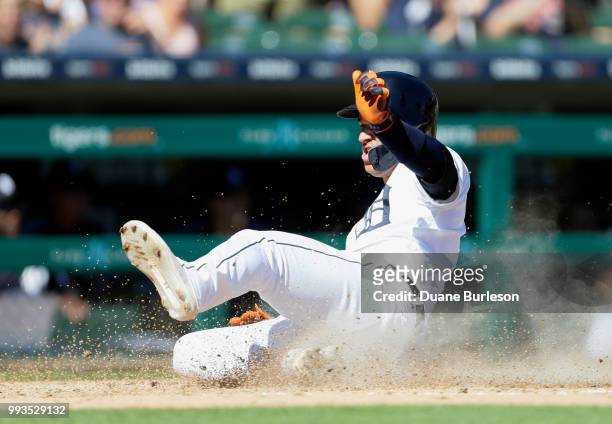 Jose Iglesias of the Detroit Tigers slides in safe at home, one one of three runs to score on an error by Delino DeShields of the Texas Rangers, who...
