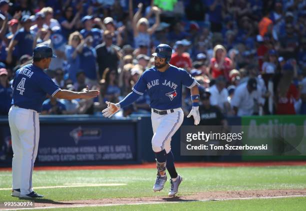 Kevin Pillar of the Toronto Blue Jays circles the bases and is congratulated by third base coach Luis Rivera after hitting a two-run home run in the...
