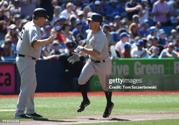 Brett Gardner of the New York Yankees is congratulated by third base coach Phil Nevin after hitting a lead-off solo home run in the first inning...